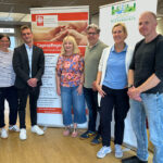 Auf dem Bild sehen sie 6 Menschen die vor zwei Bannern stehen. Es handelt sich um Mitarbeiter der SAPV Niederrhein und der Caritas Wesel-Dinslaken